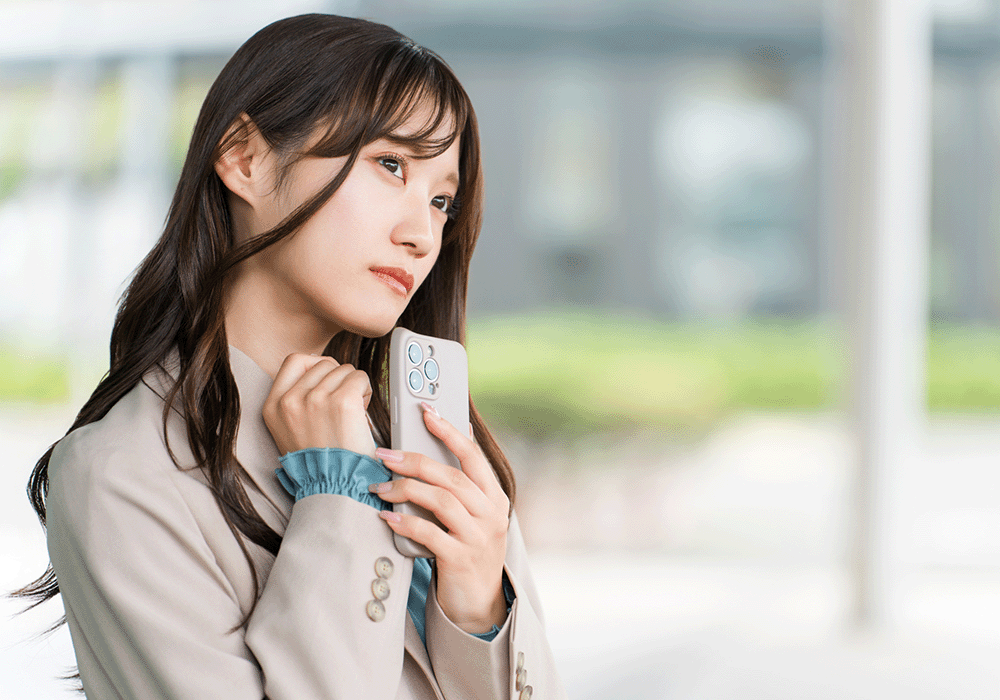 スマホをもちながら悩む女性